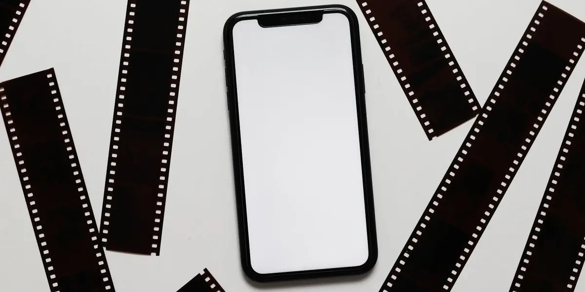 Smartphone zwischen alten Filmstreifen auf hellem Untergrund